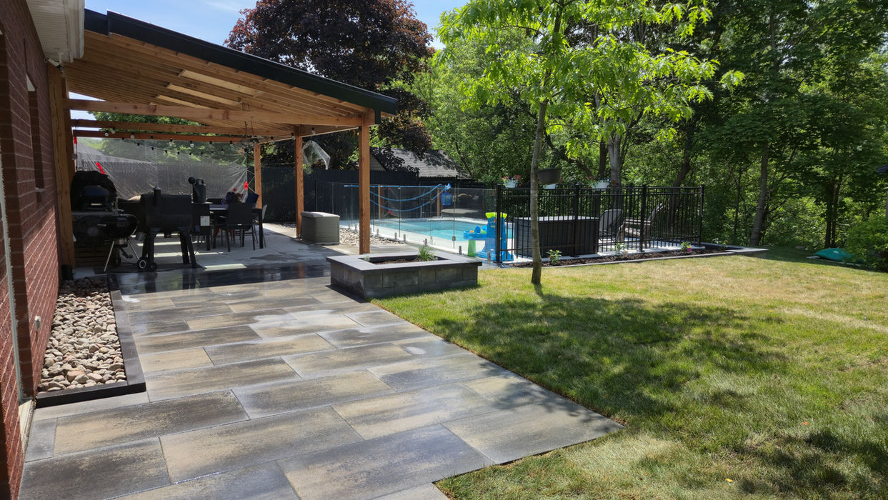 Terrasse couverte en bois avec pavé multicolore, coin repas extérieur et piscine creusée avec clôture