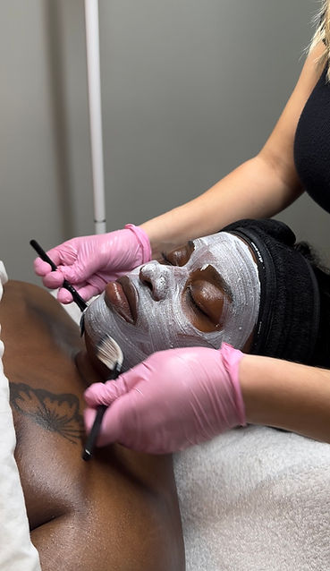 Esthéticienne appliquant un masque pour visage blanc avec des pinceaux sur une cliente