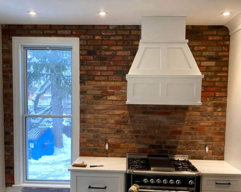 Mur de brique rouge et cuisine blanche.