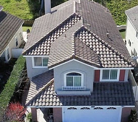 Aerial view of two suburban homes with tiled roofs, highlighting the need for roofing services.