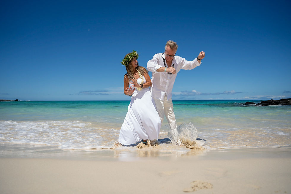 Thumbnail: “Couple plays at shoreline in wedding attire, waves and turquoise sea near Kona Wedding Officiant.”