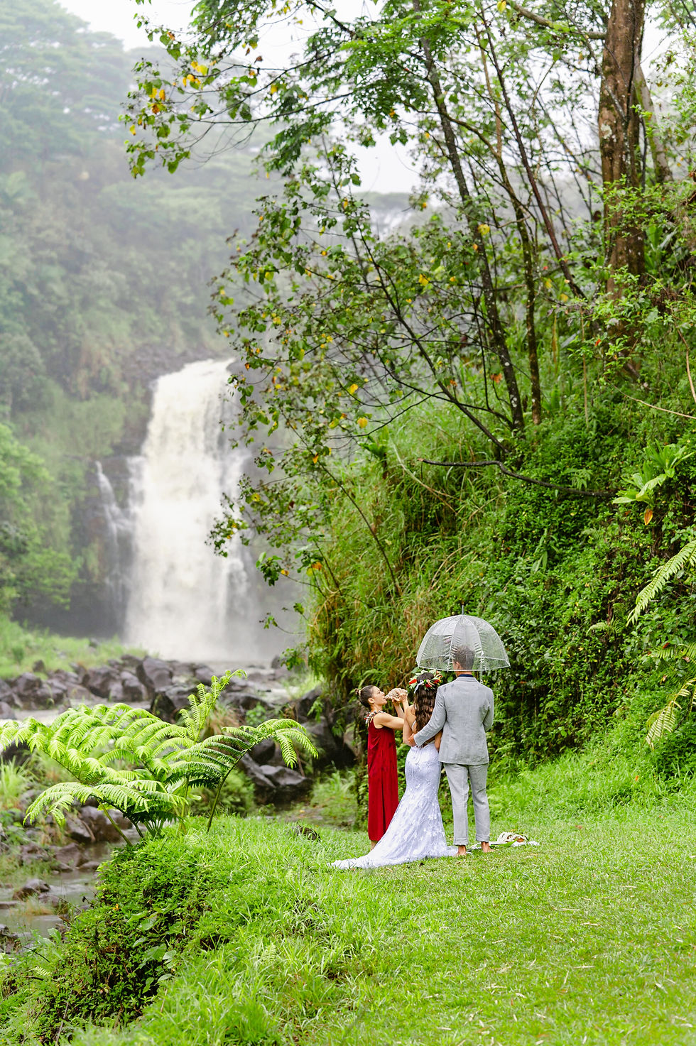 Hawai‘i wedding officiant, Deanna DiMichele, Kona Wedding Officiant, leading a heartfelt elopement ceremony with the waterfall in the background at Kulaniapia Falls.