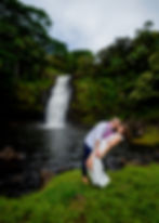 Couple stands near waterfall in Kailua-Kona—Kona Wedding Officiant elopement with lush greenery, flo