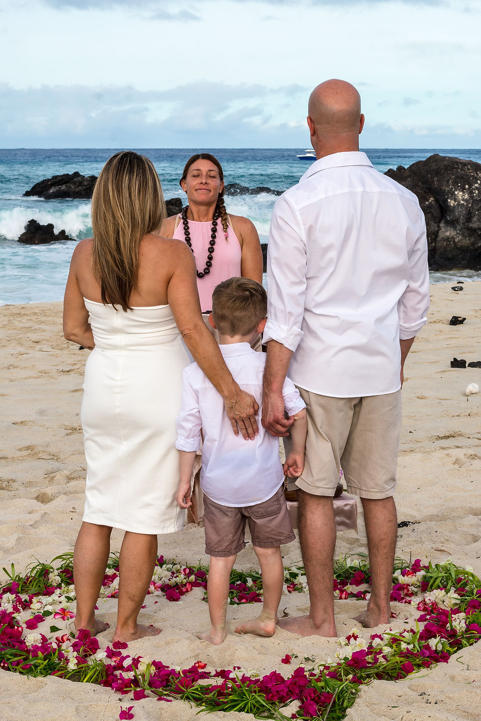Thumbnail: “Family stands in heart of petals, beachside ceremony led by Kona Wedding Officiant.”