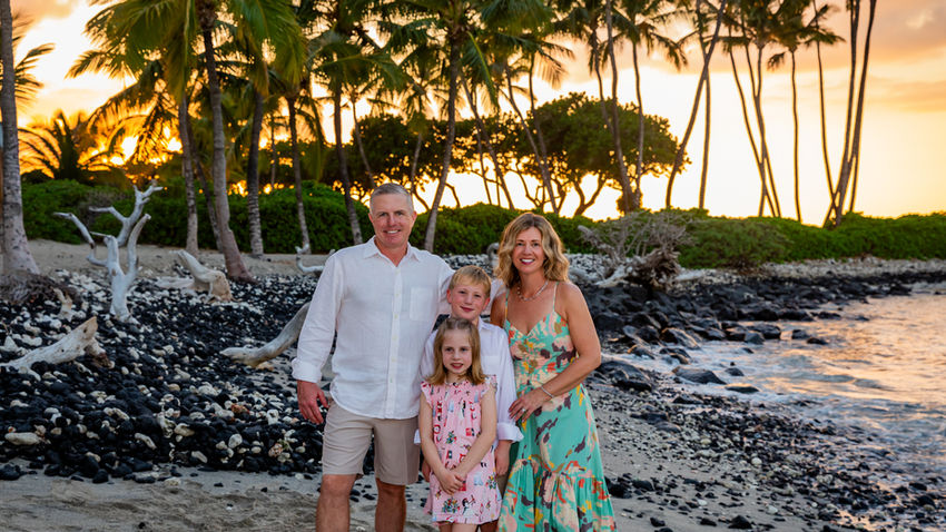 Family of 5 poses during sunset on a black and white sandy beach with Kona Photographers.