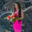 Thumbnail: Person in pink stands on lava rocks with vibrant bouquet and long dark hair in Big Island light.