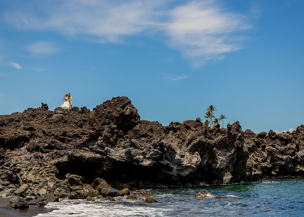 Couple posing atop volcanic lava cliffs at Kiholo Bay Black Sand Beach Hawaii.