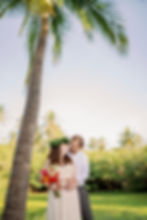 Couple facing each other under palm canopy on Punaluu Black Sand Beach, backing the pond, dressed in formal attire.