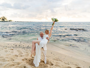 Bride in lightweight beach wedding dress for a Hawaii elopement holding tropical bouquet on Kona coastline.