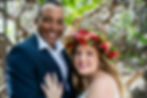 Thumbnail: Couple stands close beneath Kona’s greenery—one in dark suit, the other in white gown with floral crown—capturing a quiet mom
