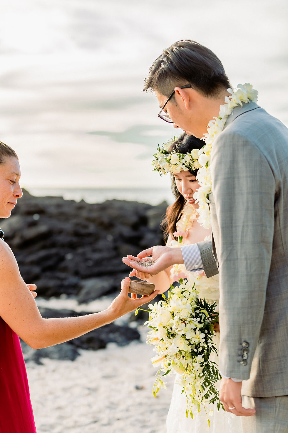 Couple exchanges vows at Holualoa Beach with Kona Wedding Officiant. Ocean backdrop, floral crown, a