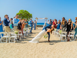 “Beachfront wedding ceremony in Kona, Hawaii with bamboo arch, floral décor, and guest seating.”