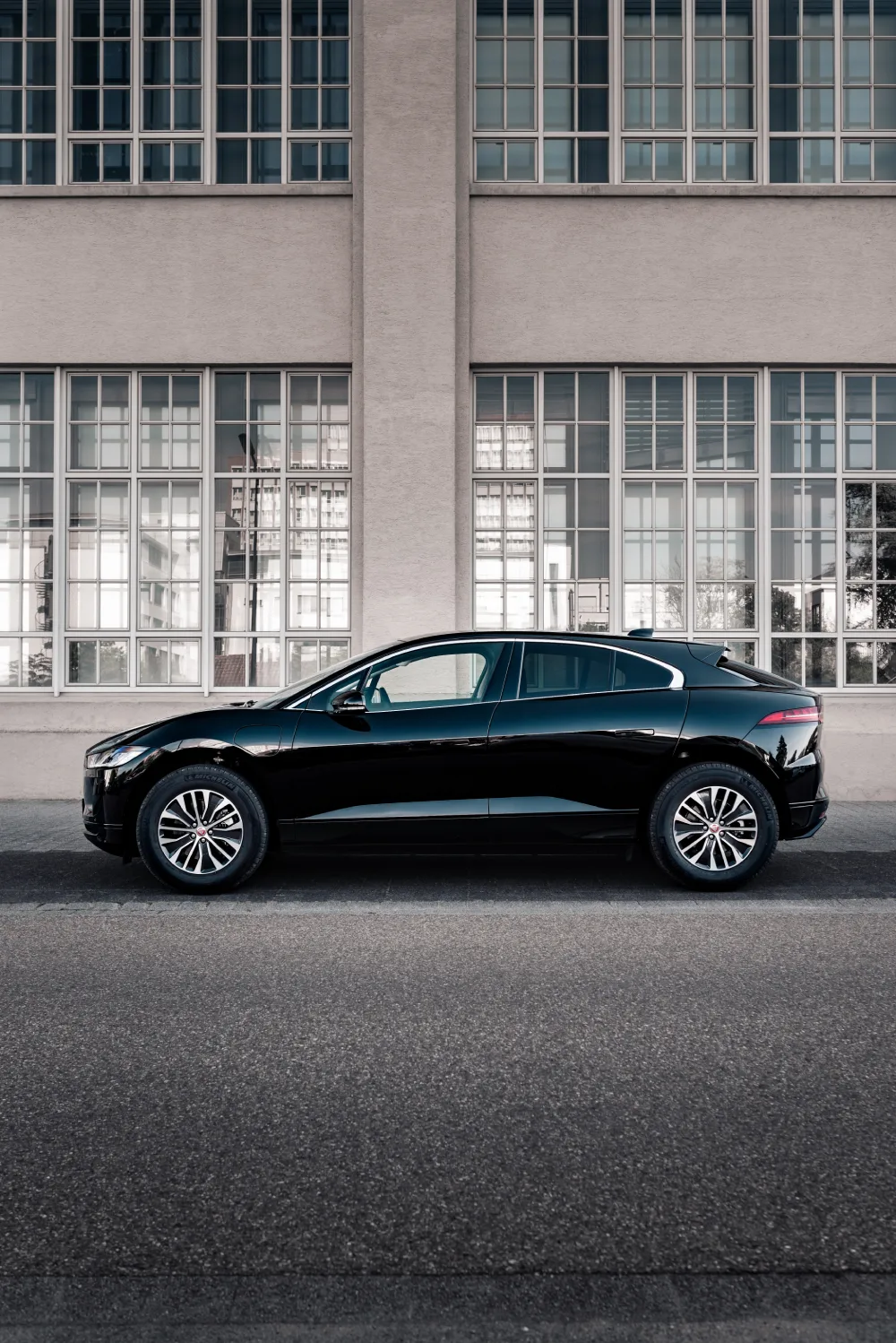 black jaguar f pace parked in street pavement opposite a building