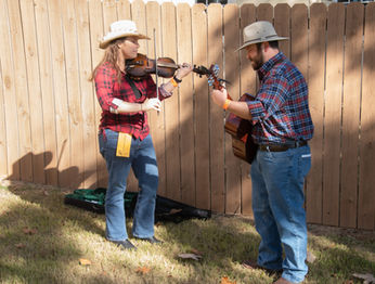 woman playing a fiddle and man playing a guitar
