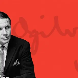 Black-and-white portrait of David Ogilvy in a suit and tie, set against a bold red background with his signature faintly visible behind him.