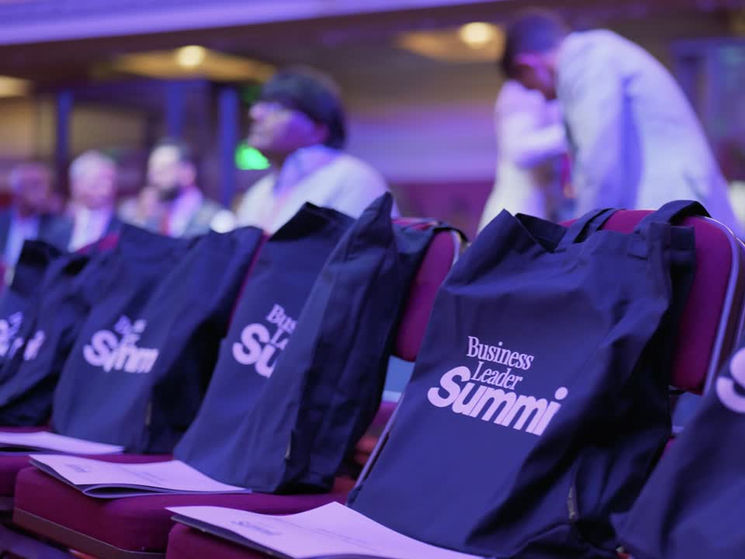 Branded tote bags on chairs at a Business Leader Summit event