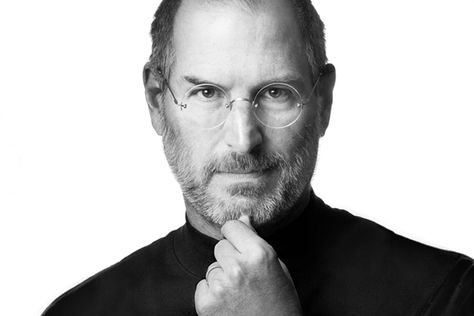 Black-and-white portrait of a man wearing glasses, resting his hand on his chin, conveying thoughtful reflection and leadership.