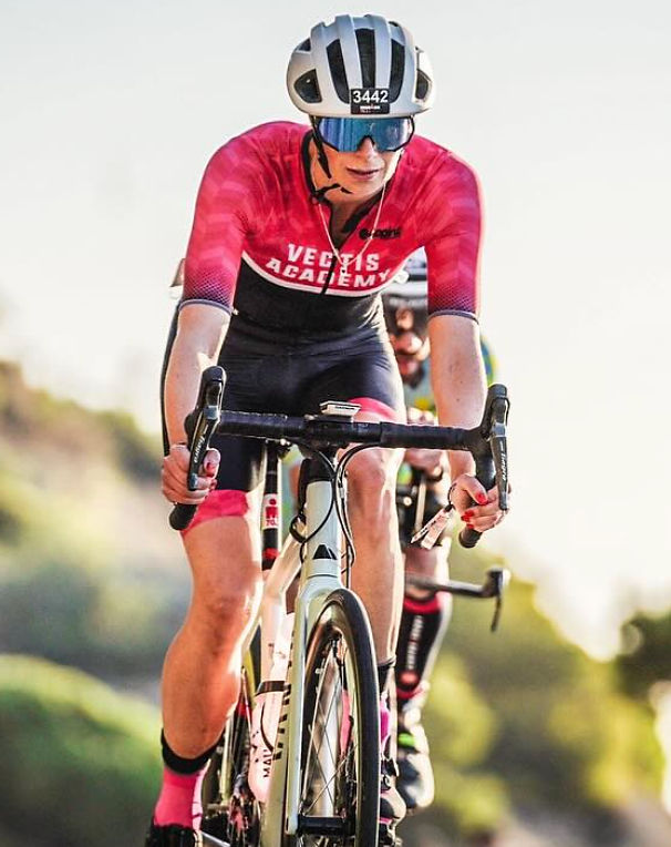 Cyclist racing in 'VECTIS ACADEMY' jersey