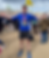 Man in blue shirt with medal, arms outspread, after race