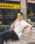 Junger Mann raucht vor einem Dönerladen und trägt dabei ein weiss Pinkes nüt. Tshirt