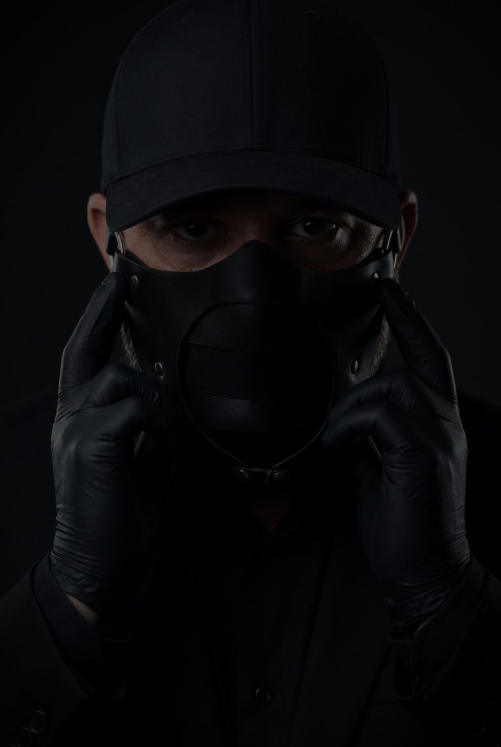 Playful Devotion masked artist adjusting mask in dark cinematic portrait