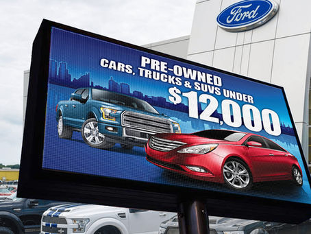 LED billboard by Matrix LED Signs displaying Ford dealership ad for pre-owned cars, trucks, and SUVs under $12,000.