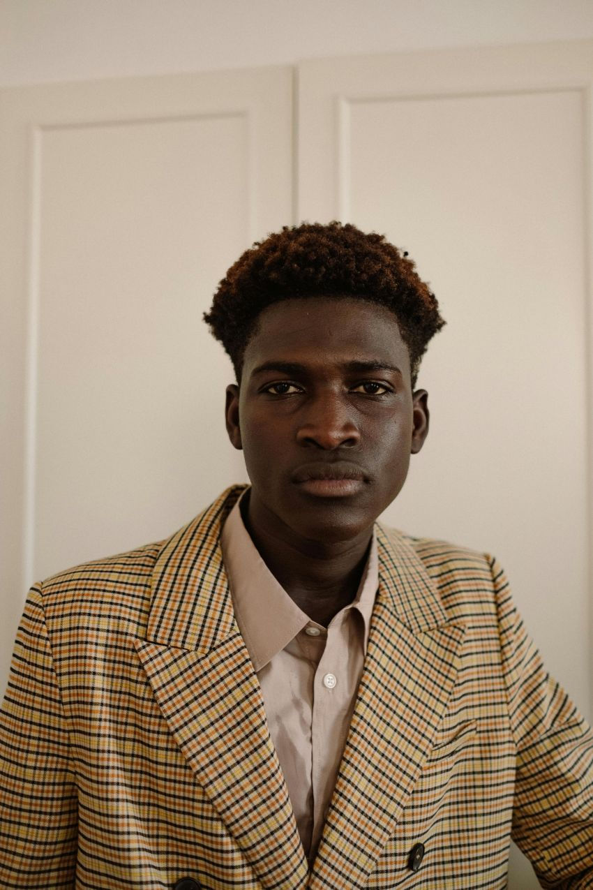 Schwarzer Man mit Lockenfrisur sieht in die Kamera