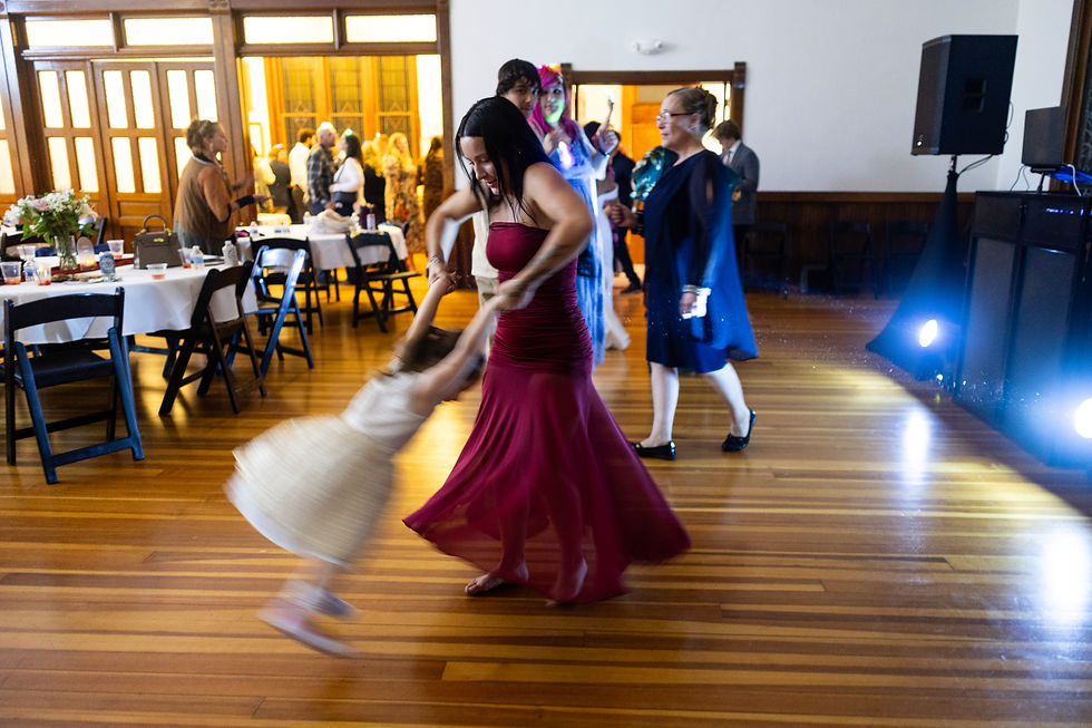 A wedding guest spins a child on the wooden reception dance floor.