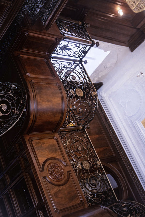 Italian Mediterranean style wood library with custom paneling, coffered ceiling, iron railing balcony, and chandelier at the Delray House Mar Pietra, custom-made woodwork.