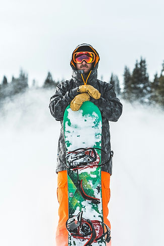 Man standing holding a green snowboard