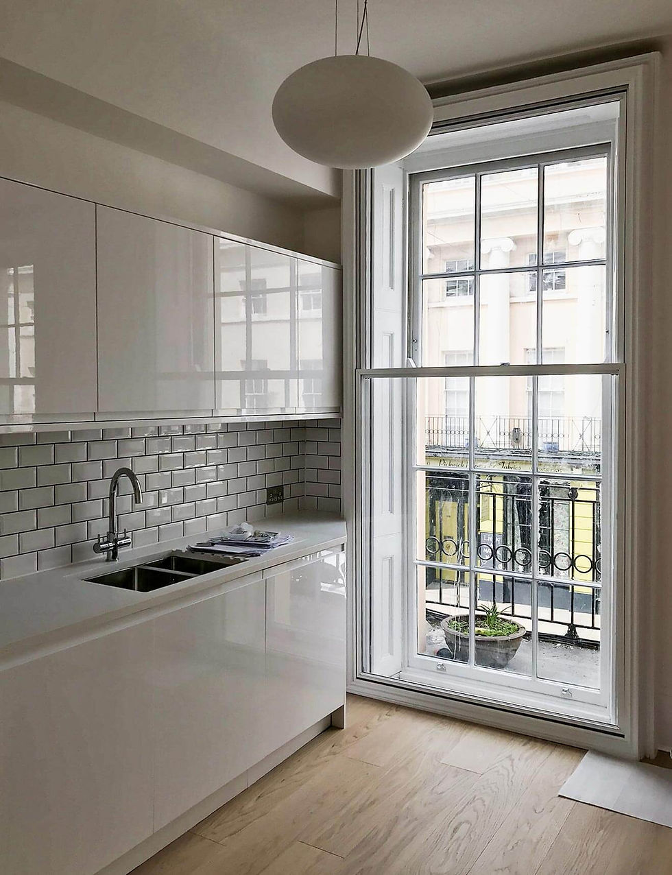 The interior of a kitcen, focusing on the tall window in the middle of the room.