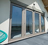 An image showing some grey patio doors leading out from a house into the garden, installed by Si Glzing Soltuions