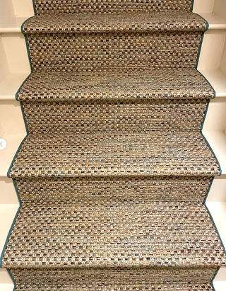A multi-colored synthetic indoor-outdoor  runner installed on painted white stairs.
