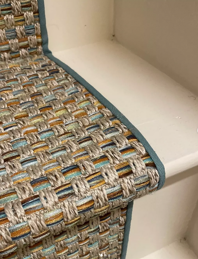 Close-up of a multi-colored olefin stair unner on white painted stairs.
