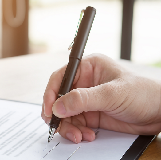 Hand holding a pen, signing a legal document with precision and authenticity