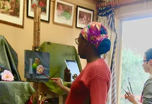 Two students painting still life in art studio