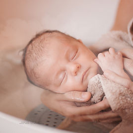 nouveau né bénéficiant d'un bain enveloppé endormi grace à la douceur du bain