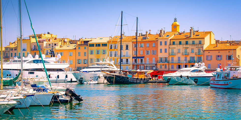 Boats docked in a vibrant harbor with pastel buildings in the background under a clear blue sky, conveying a peaceful coastal atmosphere.