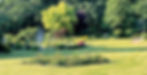 MartinsHof Grabow | Blick in den grünen Garten mit vielen Bäumen, Büschen, Blumen und Springbrunnen.