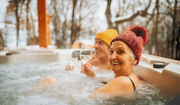 Happy couple in hot tub winter with glass of wine