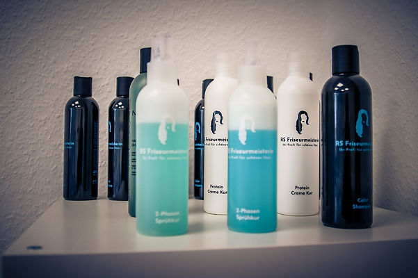 Haarpflegeprodukte stehen im Regal, mit dem Text RS Friseursalon, sowie Sprühflaschen