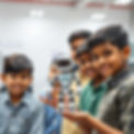 3 Young indian kids group with 15 years of age smiling holding a mini humanoid robot in on