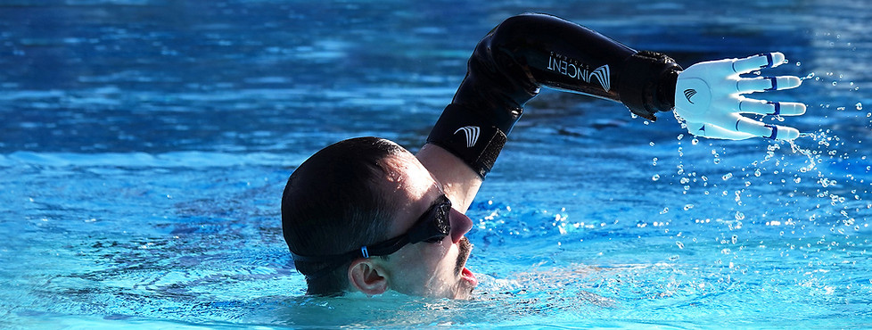 Person schwimmt im Pool und nutzt dabei eine wasserdichte Handprothese, die aus dem Wasser gehoben wird.
