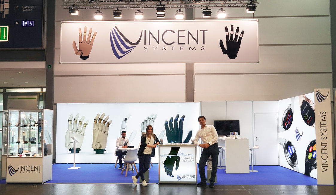 Messestand von Vincent Systems auf der OTWorld 2022 mit Präsentationsflächen für Handprothesen und Gesprächen mit Besucherinnen und Besuchern