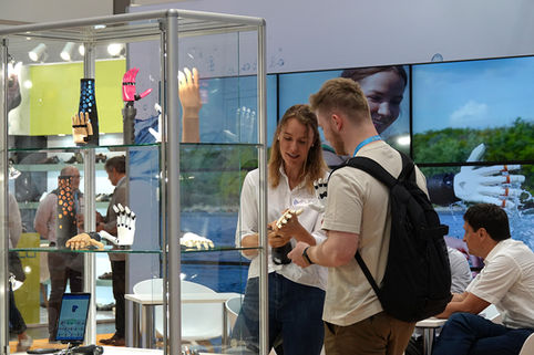 Beratungsgespräch an einem Messestand: Zwei Personen tauschen sich über eine Handprothese aus