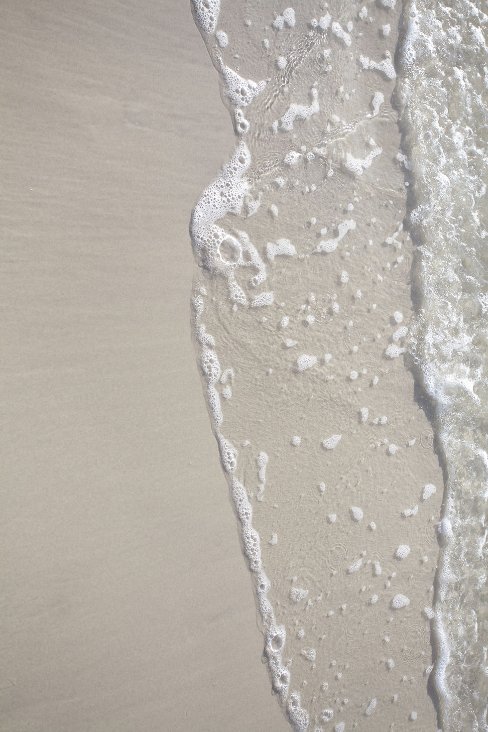Sanfter Übergang von Sand zu Wasser – Symbol für Übergang von Klinik zur häuslichen Pflege