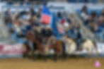 Riders on horseback holding flags during a trail ride.