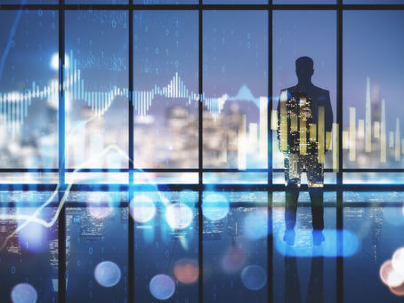 man standing, looking at skyline with financial data and charts