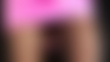 Madame Sami in a pink skirt, fishnet stockings, and black boots, making a pointing gesture. Background is dark. Bold and edgy.