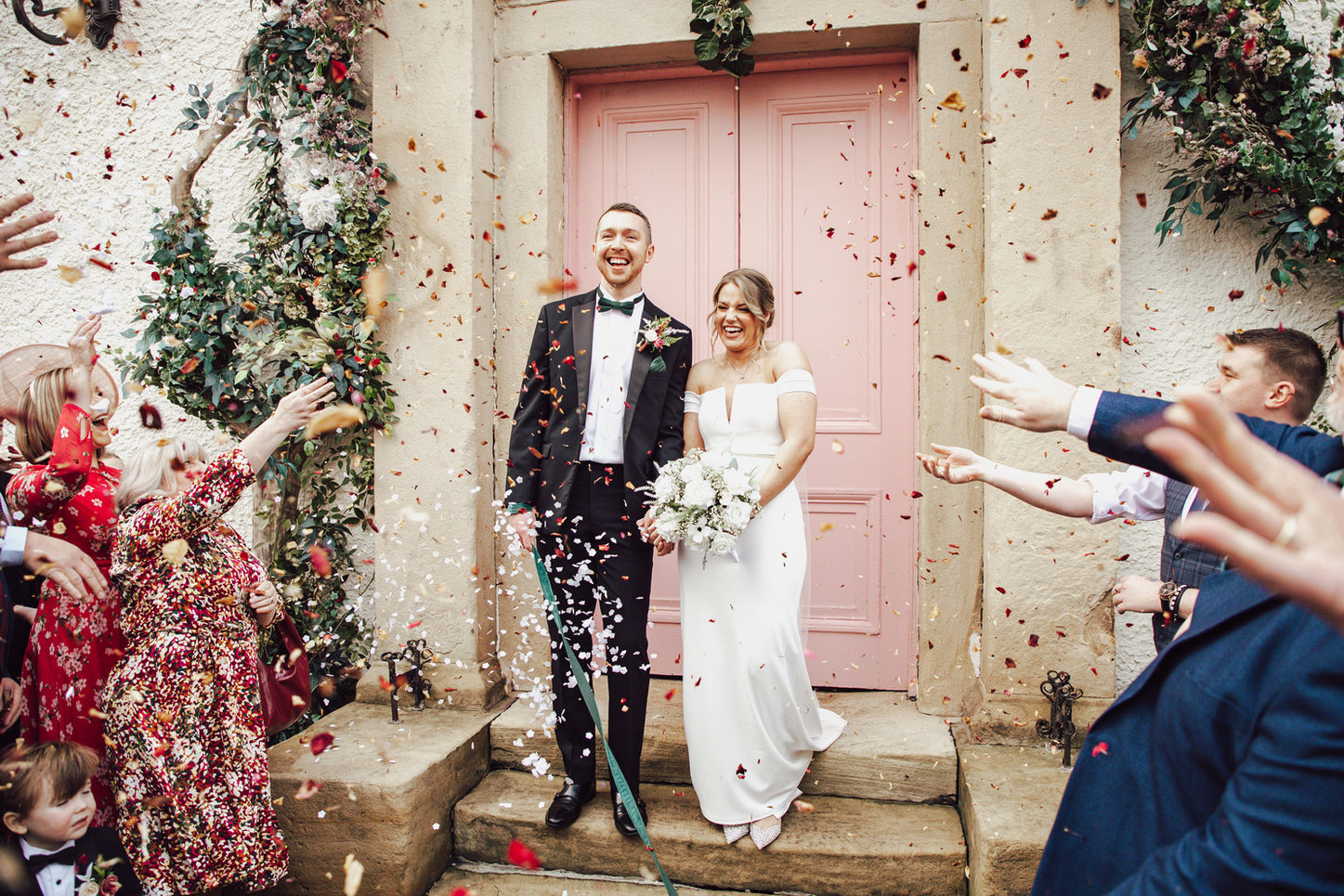 Phoebe & Joshua laughing together during a confetti moment after their wedding ceremony at The Croft Hotel, candid joyful wedding photography.